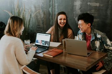 Three people collaborating around laptops during a lesson